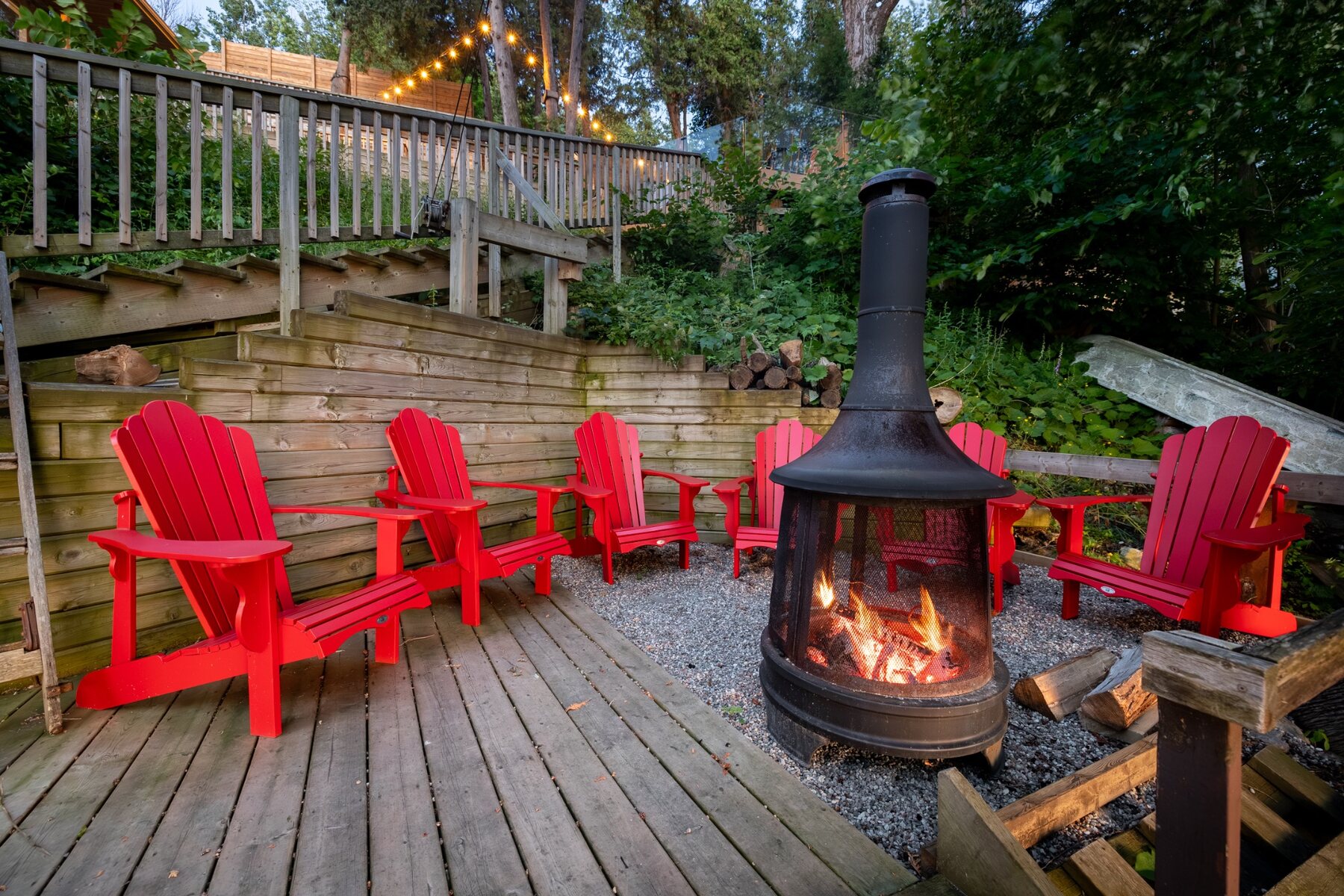 Outdoor fire pit surrounded by red Adirondack chairs